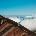 Person walking on the 7-color mountain admiring the view of the clouds.