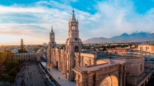 Panoramic photograph of the Plaza de Armas with the Arequipa Cathedral in the background, white architecture and clear sky.