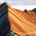 Panoramic view of Rainbow Mountain Peru (Vinicunca) with colorful mineral stripes and the Ausangate range in the background, seen during the Rainbow Mountain tour from Cusco.