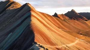 Panoramic view of Rainbow Mountain Peru (Vinicunca) with colorful mineral stripes and the Ausangate range in the background, seen during the Rainbow Mountain tour from Cusco.