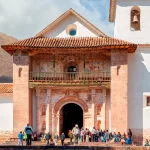 Photograph of the interior with murals, gilded altars, and colonial art.
