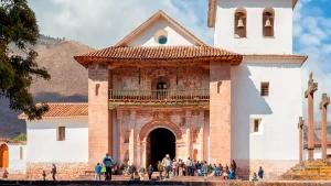 Photograph of the interior with murals, gilded altars, and colonial art.